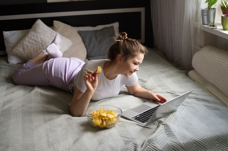 dziewczyna jedząca czipsy na łóżku